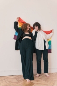 two people looking at each other and holding a rainbow flag around them