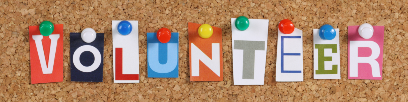 Cut outs from magazine that spell out "Volunteering" pinned on a cork board