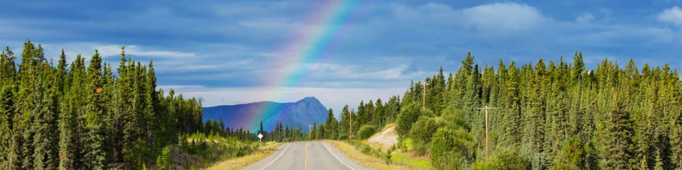 natural rainbow over road in front of a mountain backdrop
