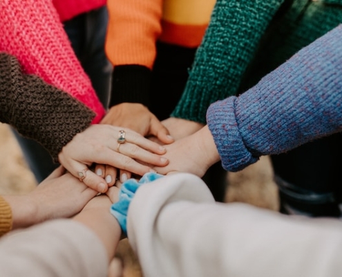 A circle of people putting their hands together in unity